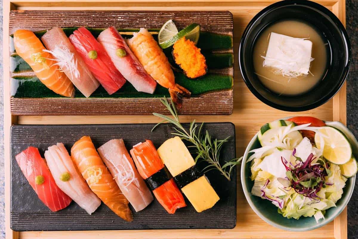 A platter of assorted nigiri sushi with miso soup and salad
