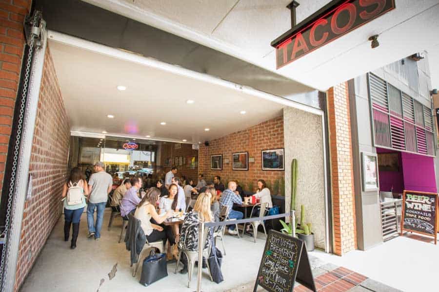 Diners inside a busy taco restaurant with an open storefront in Downtown Burbank