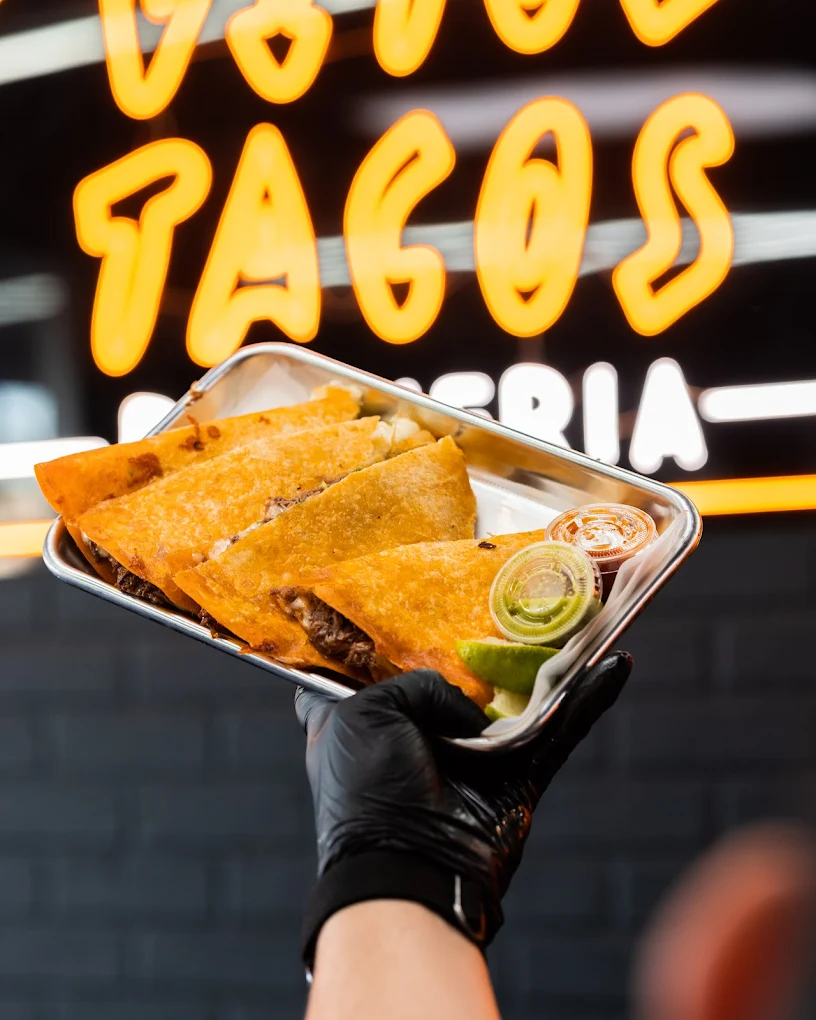 Hand holding a pan of tacos from Vito's Tacos'