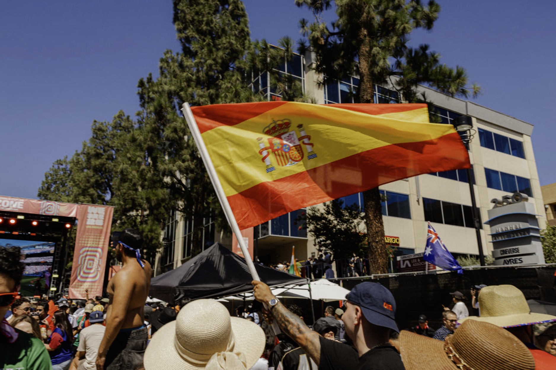A fan waves a large Spain flag in the crowd near the Fan Zone concert stage