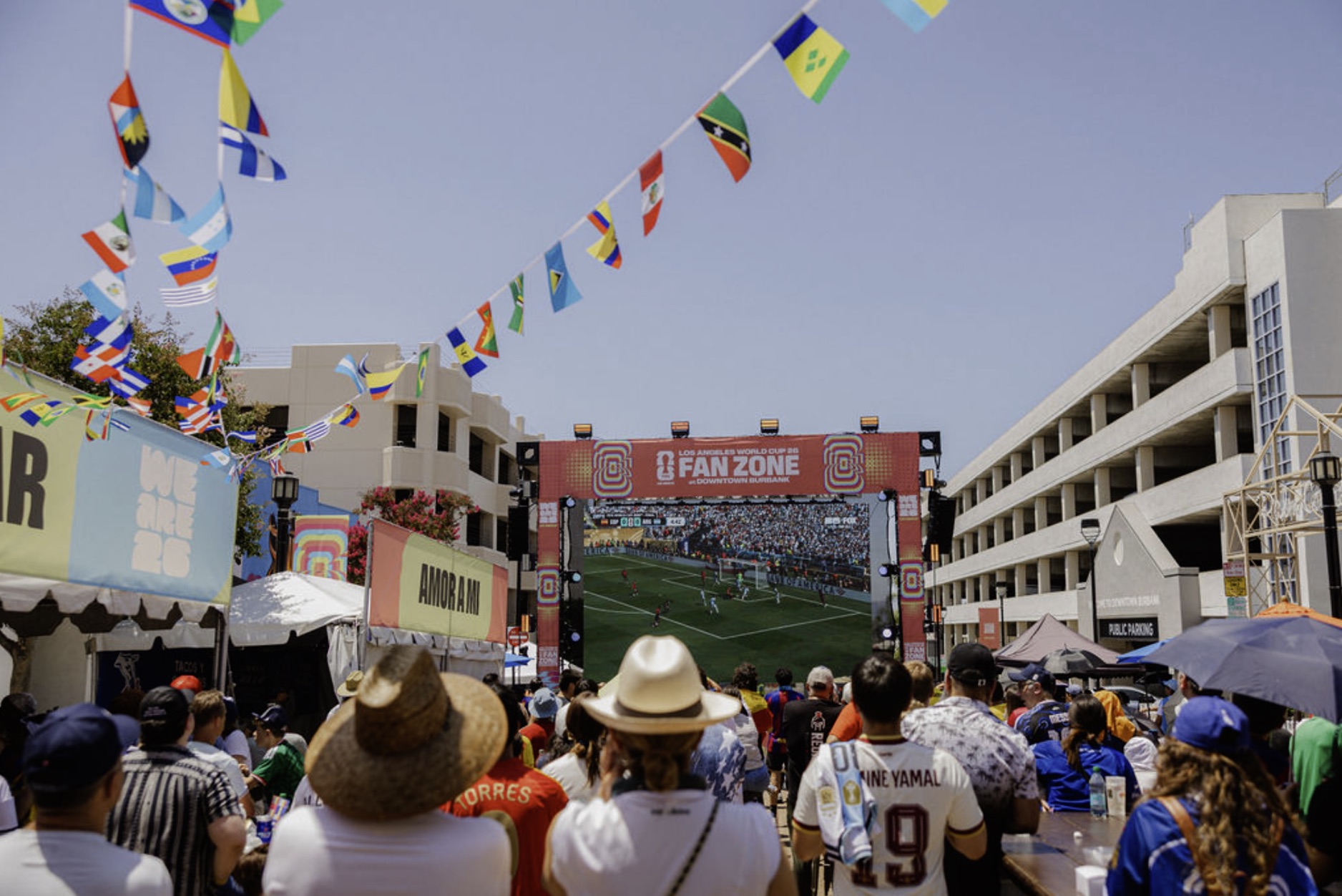 Crowds under strings of international flags watch a World Cup match on the Fan Zone big screen in Downtown Burbank